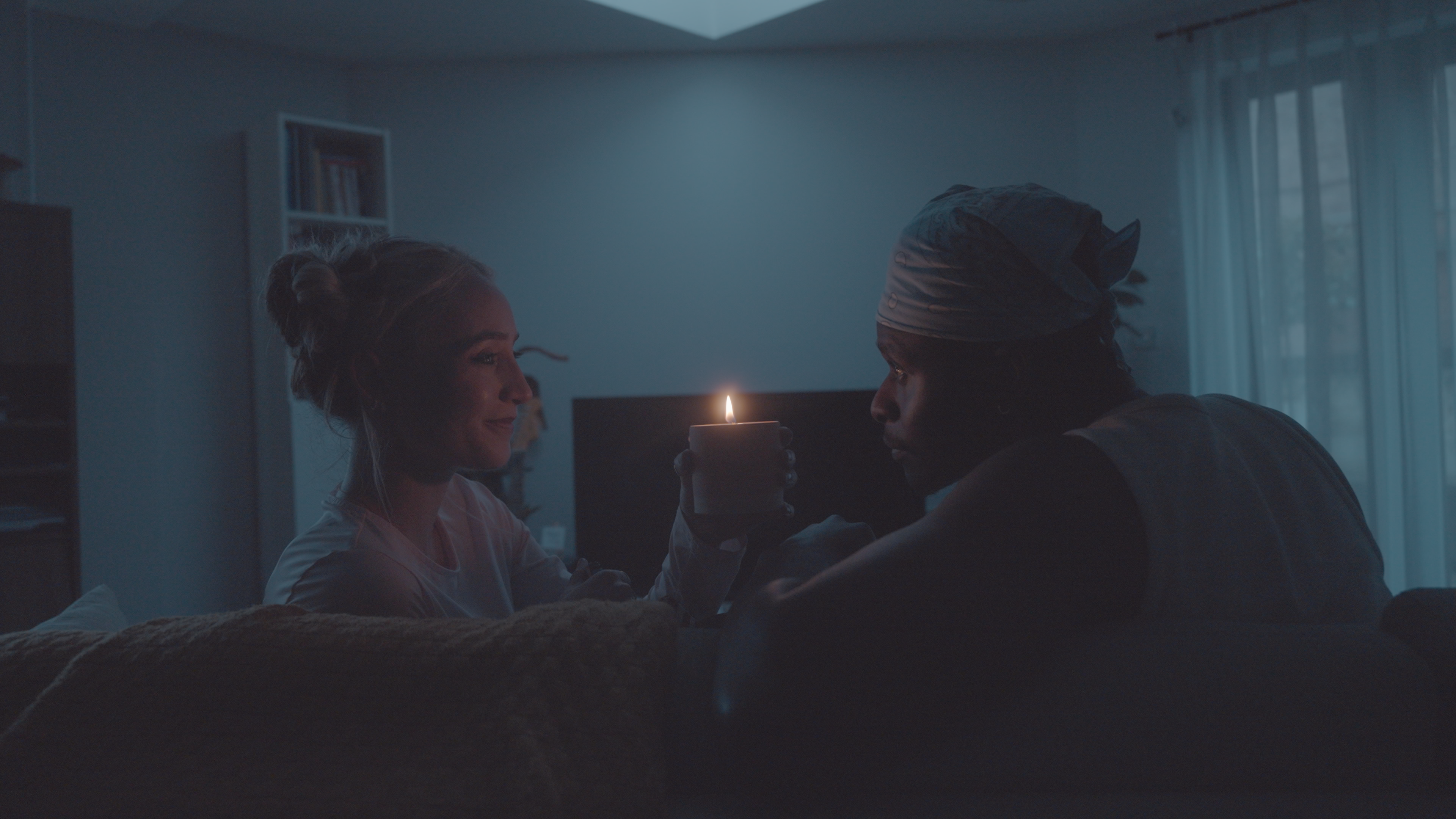Two people sharing a quiet moment, connecting over a lit ThirdWall candle in a dimly lit room.
